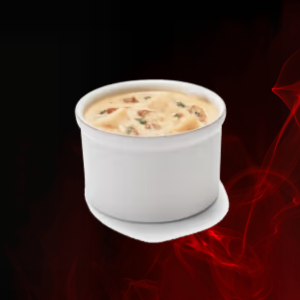 Creamy loaded potato soup served in a cup, topped with crispy bacon, shredded cheddar, and fresh chives—comforting and hearty.